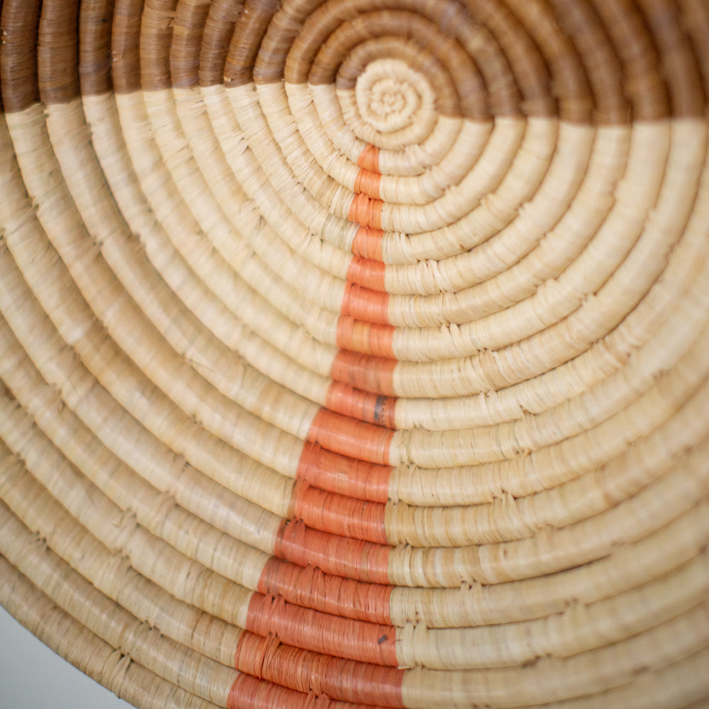 JustOne's two-toned tan wall basket with small pink sliver, handwoven in Uganda