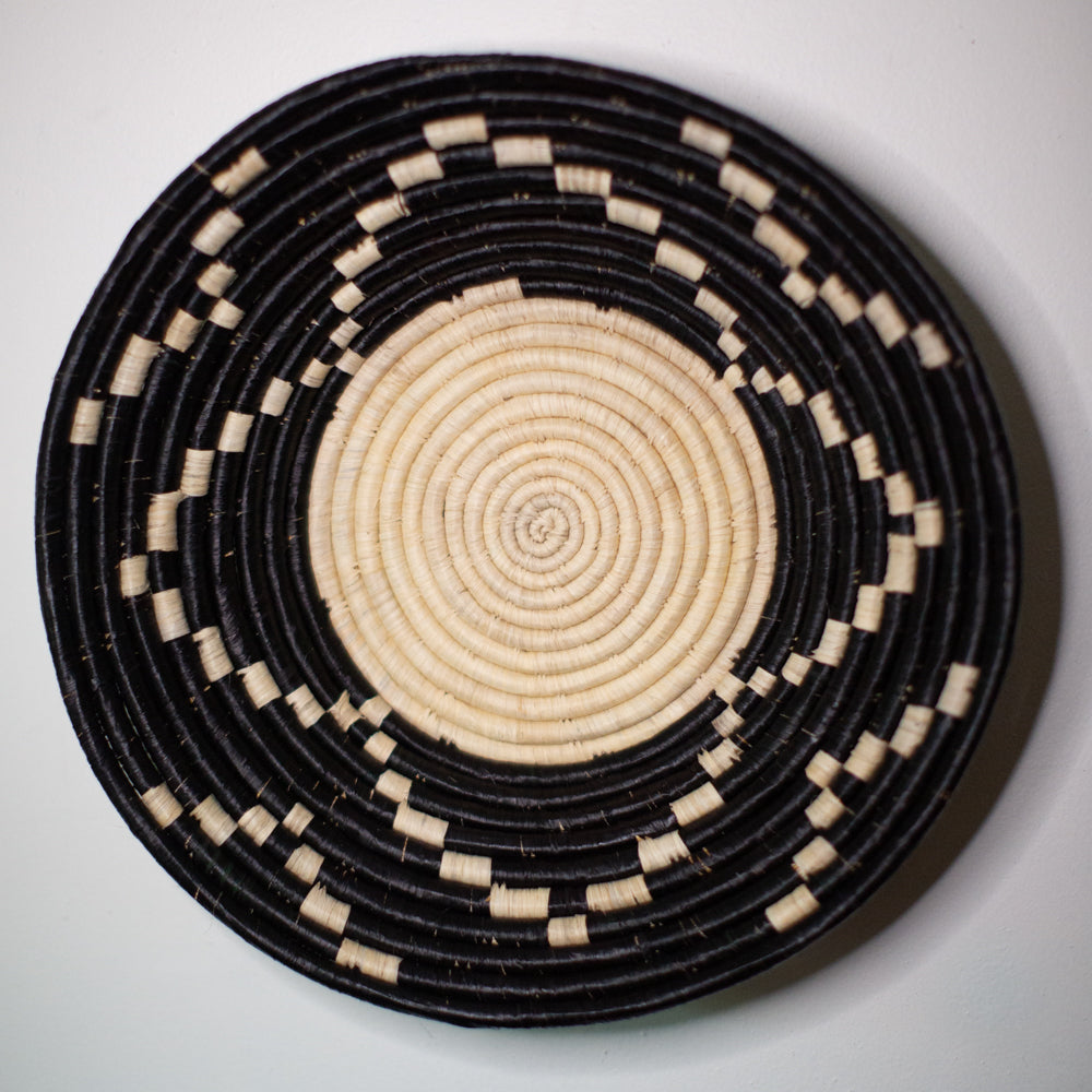 JustOne's black wall basket with tan designs, handwoven in Uganda