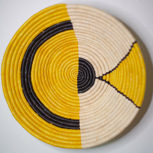 JustOne's yellow, black, and tan wall basket. handwoven in Uganda
