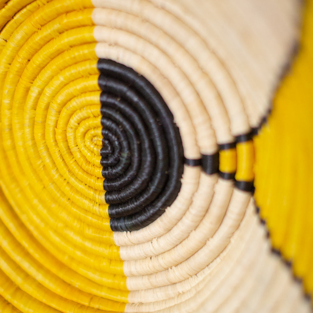JustOne's yellow, black, and tan wall basket, handwoven in Uganda