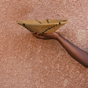 JustOne's tan basket with black lines handwoven in Uganda