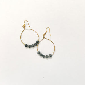JustOne's brass hoop earrings with five grey paper beads on the bottom of the hoop, handcrafted in Uganda