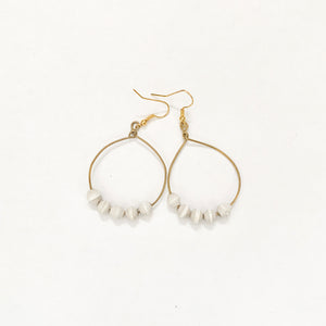 JustOne's brass hoop earrings with five white paper beads on the bottom of the hoop, handcrafted in Uganda