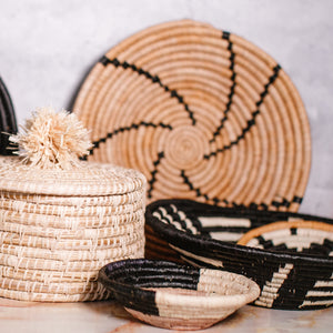 JustOne's tan basket with black lines handwoven in Uganda