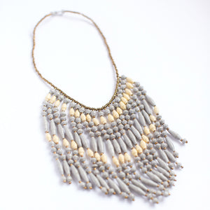 JustOne's necklace with several dangling strings of paper beads in grey and tan colours, handcrafted in Uganda