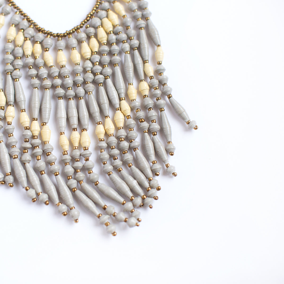 JustOne's necklace with several dangling strings of paper beads in grey and tan colours, handcrafted in Uganda
