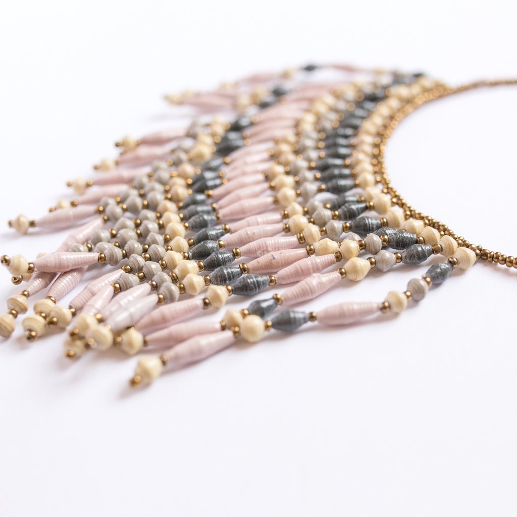 JustOne's necklace with several dangling strings of paper beads in grey, pink, and tan colours, handcrafted in Uganda