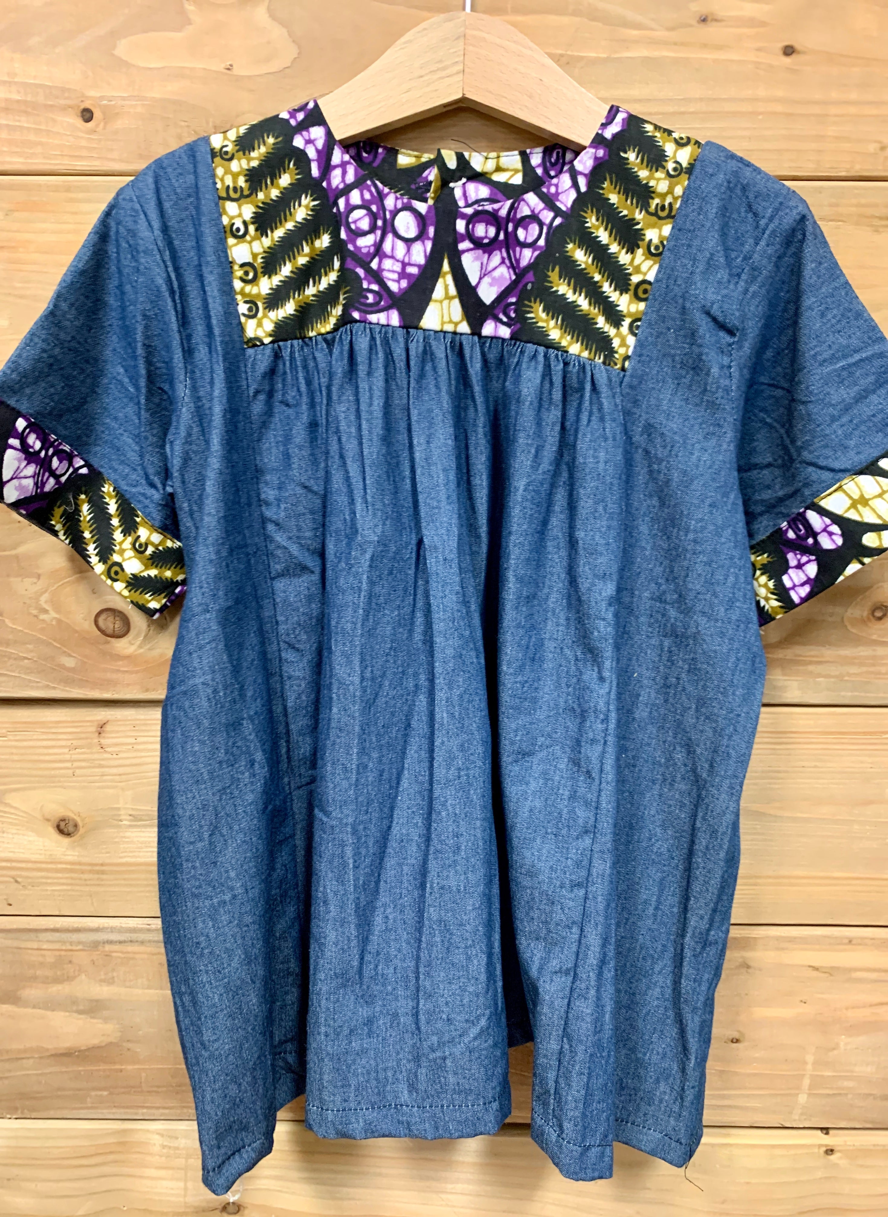 JustOne's small blue dress with design around the collar and cuffs of the sleeves, hand-sewn in Uganda