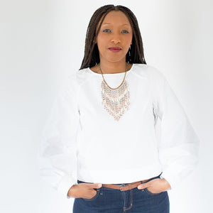JustOne's necklace with several dangling strings of paper beads in muted grey, pink, and tan colours, handcrafted in Uganda
