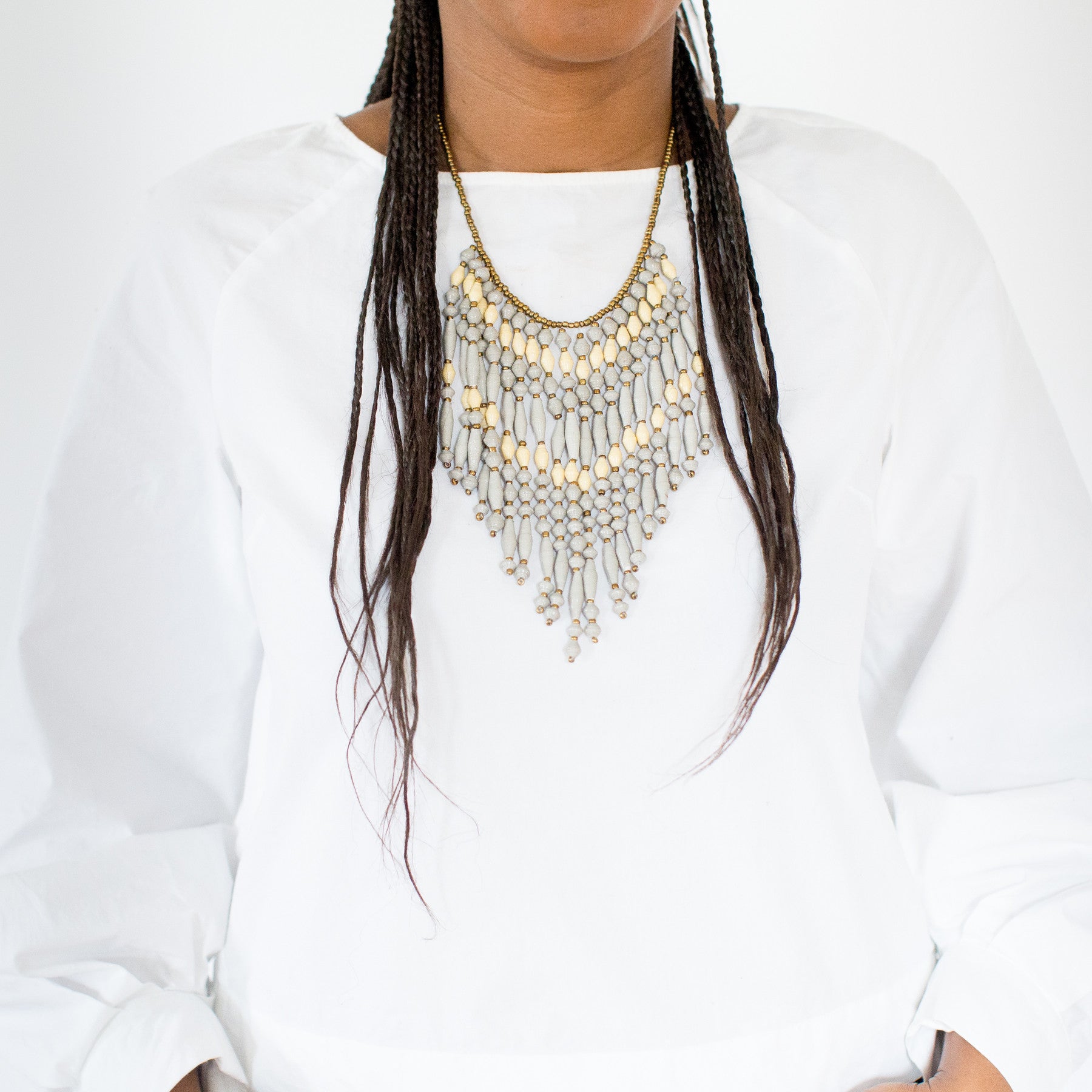 JustOne's necklace with several dangling strings of paper beads in grey and tan colours, handcrafted in Uganda