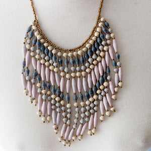 JustOne's necklace with several dangling strings of paper beads in grey, pink, and tan colours, handcrafted in Uganda