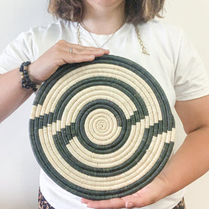 JustOne's large flat basket with tan and dark green twisting around the circle, handwoven in Uganda