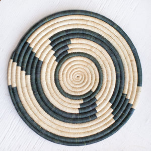 JustOne's large flat basket with tan and dark green twisting around the circle, handwoven in Uganda